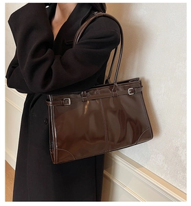 Macro detail of the dark brown glossy oil wax leather texture and silver buckle on tote