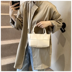 Detail of cream woven tote bag featuring round handles and a detachable shoulder strap