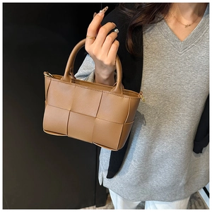 Detail of caramel woven leather handbag with intreciatto pattern and round handle