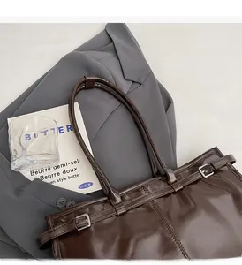 Detail of deep brown tote bag featuring glossy oil-wax leather and adjustable straps