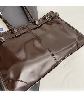 Macro shot of dark brown glossy oil wax leather bag texture with neat stitching detail