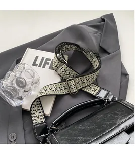 Detail der schwarzen Lederumhängetasche mit grünem gewebtem Schultergurt auf einem Blazer