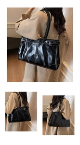 Detail of glossy black leather tote bag featuring side buckle straps and a retro structure