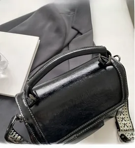 Detailansicht der schwarzen Retro-Handtasche mit ethnischem Web-Schultergurt und Metallhaken