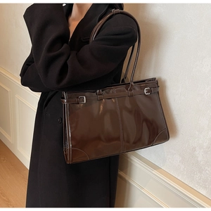 Deep brown glossy patent leather tote bag detail with decorative metal buckle strap