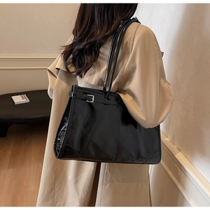 Detail showing high-gloss black tote bag with dual straps and side metallic buckle