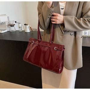 Detail of burgundy patent leather tote bag with glossy finish and metal buckle