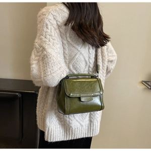 Olivgrüne glänzende Umhängetasche an einem Model mit Jacquard-Gurt für den Alltag