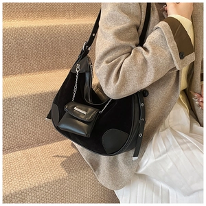 Detail of black crescent hobo bag with silver chain charm and retro eyelet strap design