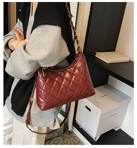 Close-up of wine red quilted leather bag with gold chain and key pendant on a model