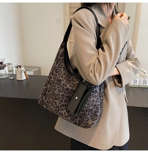 Close-up of leopard print hobo tote bag with black leather strap and matching small pouch