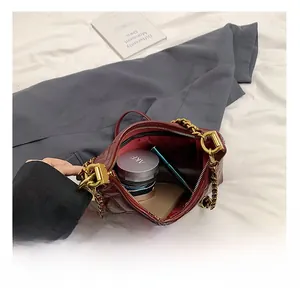 Detail view of burgundy quilted leather handbag interior with gold chain and essentials