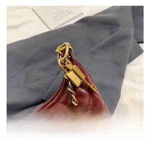 Detail shot of wine red quilted leather bag showing gold chain strap and ornate lock