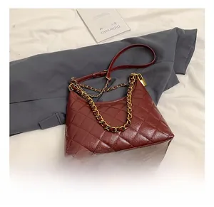 Detail of burgundy quilted leather bag featuring gold chain and padlock charm