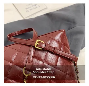Detail of adjustable shoulder strap on red quilted leather bag with gold buckle