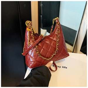 Detail of burgundy quilted leather hobo bag with gold chain and key charm accessory