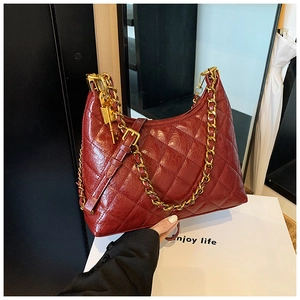 Detail of red quilted faux leather handbag with gold chain strap and padlock charm