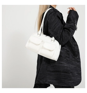 Close-up of a white leather shoulder bag with two front pockets on a model