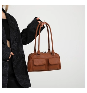 Close-up of brown litchi pattern leather shoulder bag with dual front pockets and silver zippers