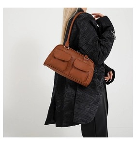 Close-up of vintage brown shoulder bag with dual flap pockets and soft leather texture