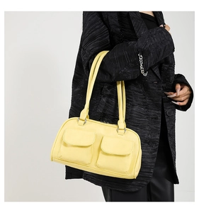 Detail of bright yellow faux leather shoulder bag with dual flap pockets and silver hardware