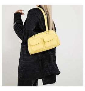 Detail of yellow underarm bag featuring dual front pockets and premium leather texture