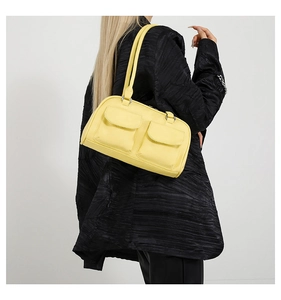 Detail shot of bright yellow faux leather shoulder bag with utility pockets and zipper closure