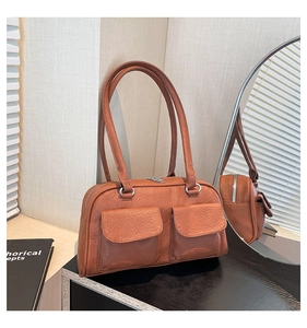Detail shot of a brown vintage shoulder bag with textured leather and front flap pockets