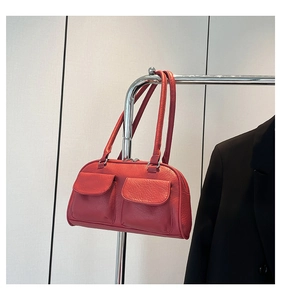 Detail of red pebbled leather underarm bag with dual front flap pockets and silver buckles