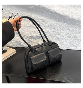 Detail of black pebbled leather underarm bag with double front flap pockets and silver zippers