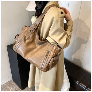 Detail einer braunen Shopper-Tasche mit Taschen getragen über einem khakifarbenen Mantel