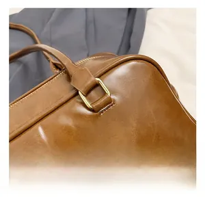 Detail of golden metal ring hardware and fine stitching on a vintage brown leather bag