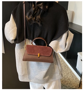 Detail of reddish-brown textured suede and smooth leather bag with gold metal clasp