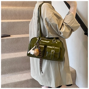 Detail of dark green patent leather Boston bag with vintage pockets and sports charms