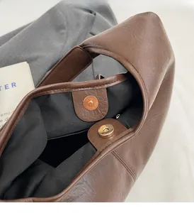 Detail of brown litchi pattern leather bag with golden magnetic clasp and black lining