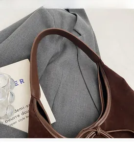 Close-up of suede shoulder bag handle and stitching detail with a vintage look