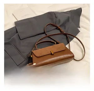 Detail of vintage brown crossbody bag featuring mixed textures and gold square lock