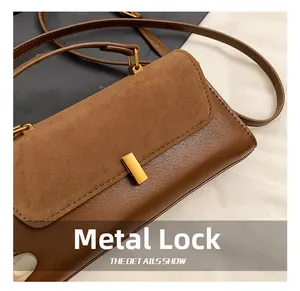 Detail of golden rectangular twist lock on brown suede and leather patchwork handbag
