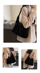 Detail of black suede shoulder bag with 3D leather bow accent and large capacity