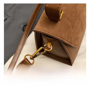 Detail shot of the golden metal hook and matte PU leather texture on a brown shoulder bag