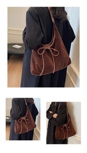 Detail of a dark brown suede tote bag with a minimalist leather bow and retro design