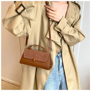 Détail du sac à bandoulière vintage marron avec patchwork en daim et boucle dorée sur manteau