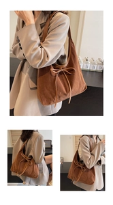Detail of a brown suede hobo bag featuring a decorative bow and wide shoulder strap