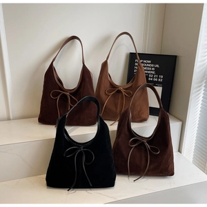 Macro display of four suede hobo shoulder bags in various winter colors with bow detail