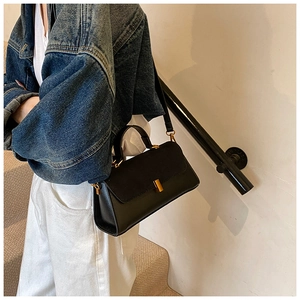 Détail d'un sac bandoulière noir avec boucle métallique dorée et texture en cuir