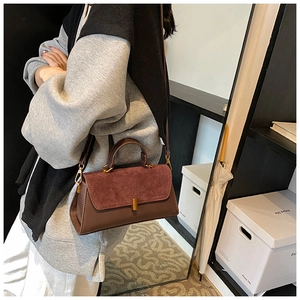Detail of dark brown and burgundy crossbody bag with contrasting suede flap