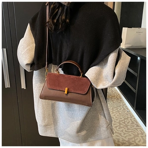 Détail d'un sac bandoulière vintage en cuir bicolore avec un fermoir métallique doré