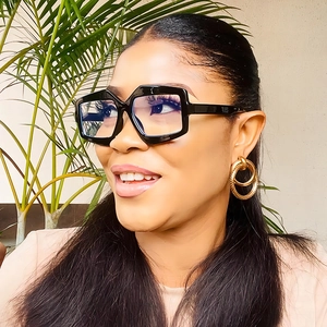 Schicke polygonale schwarze Oversize-Brille und goldene strukturierte Creolen an einem Model