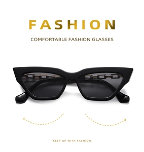Détail de lunettes de soleil œil-de-chat noires avec des éléments de chaîne dorée sur les branches