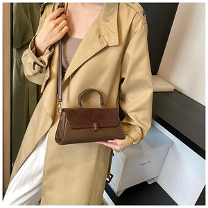 Détail du sac à main marron avec rabat en daim, cuir lisse et boucle en métal doré
